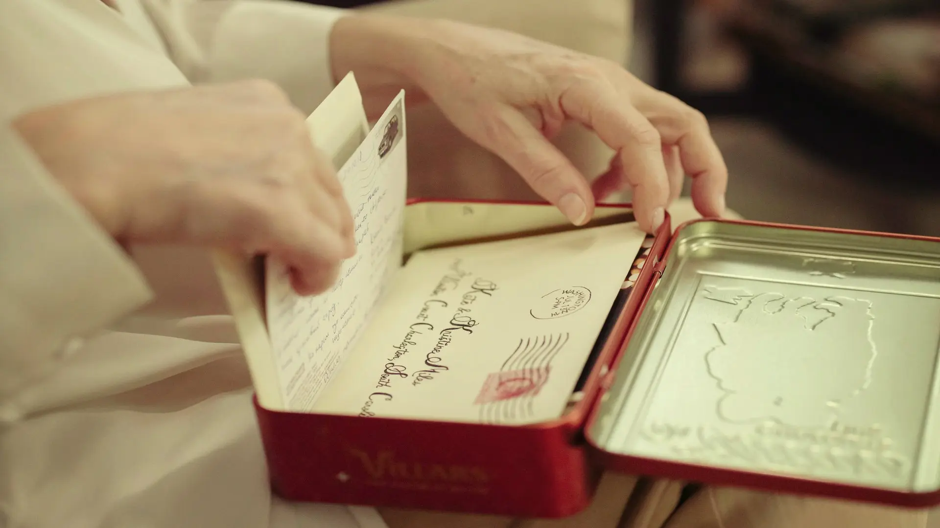 Elderly lady looking through a tin of handwritten received letters