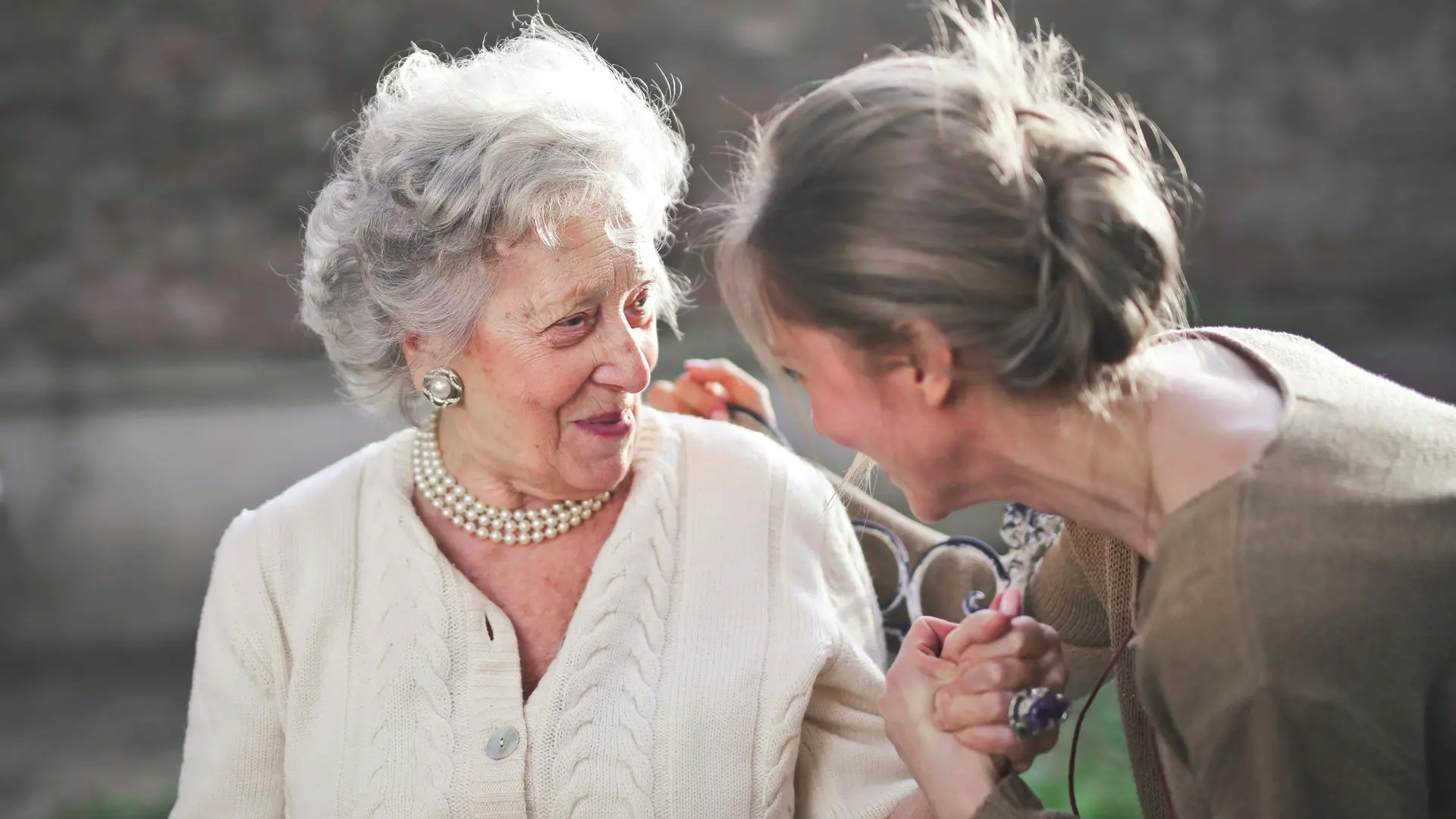 Mother and daughter holding hands on a bench looking into each others eyes