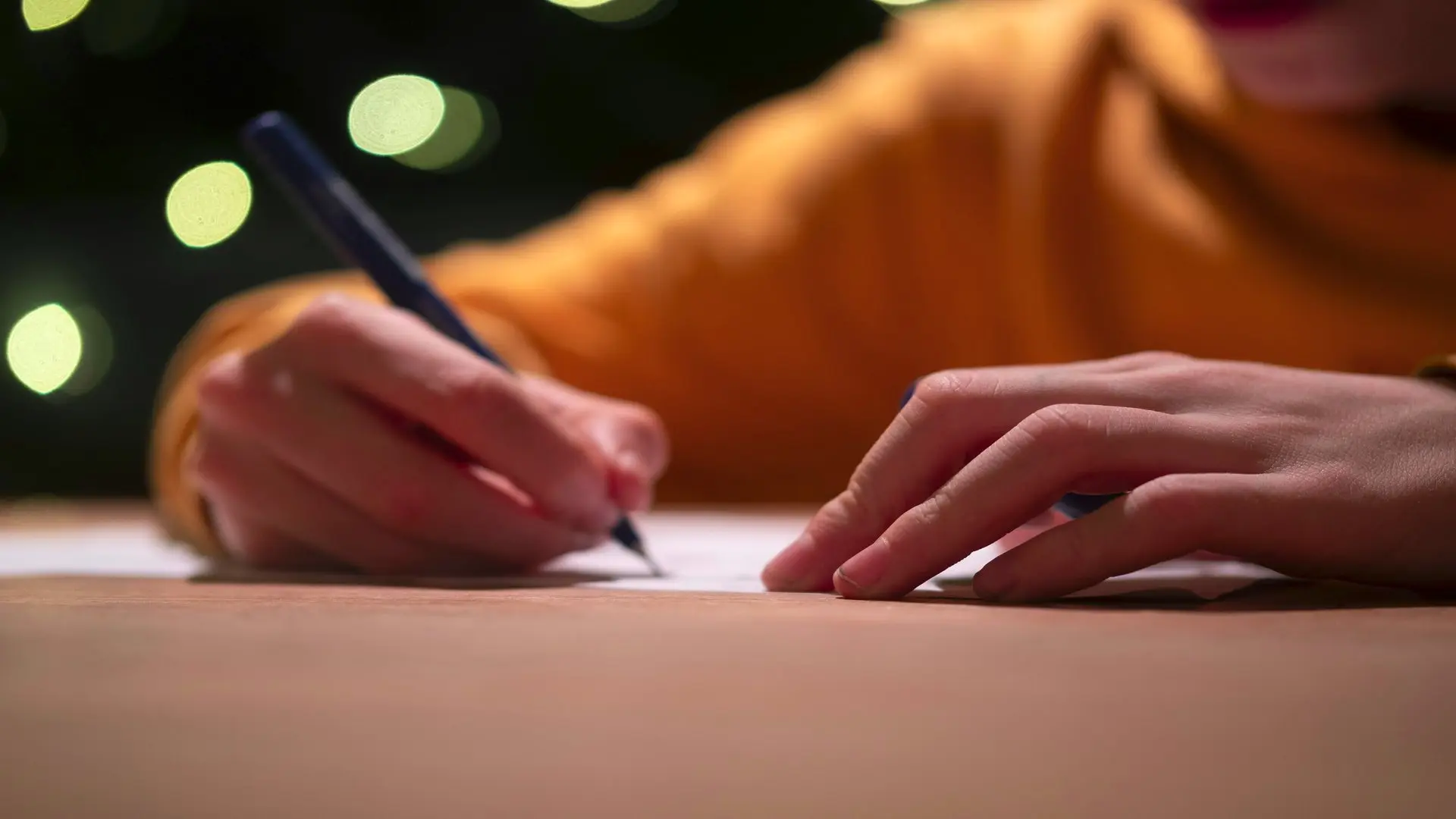 Persons hands with pen in hand writing a letter telling their story